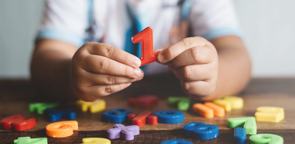 Child holding plastic toy number one, she is learning to count. Concept of child education and child growth